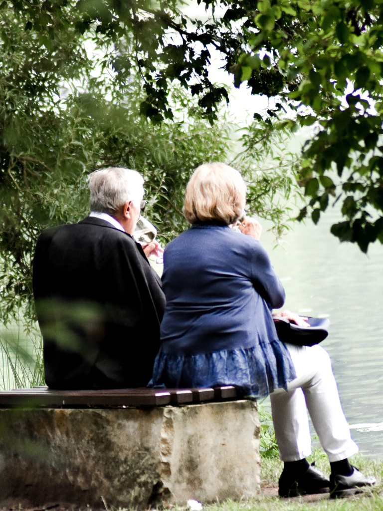 Seniorin und Senior auf einer Parkbank am See